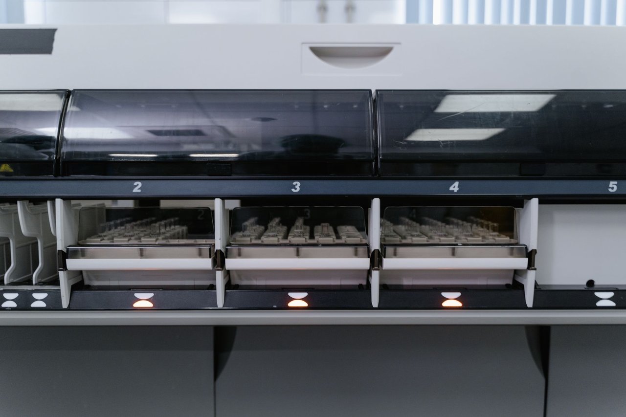 Máquina automatizada de laboratório analisando várias amostras em uma unidade de pesquisa em saúde.