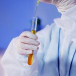 Cientista usando equipamentos de proteção realiza um teste com um tubo em um laboratório.