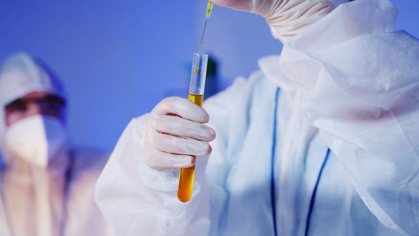 Cientista usando equipamentos de proteção realiza um teste com um tubo em um laboratório.