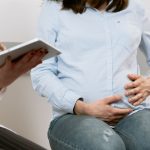 Gestante conversa com profissional de saúde durante uma consulta de pré-natal.