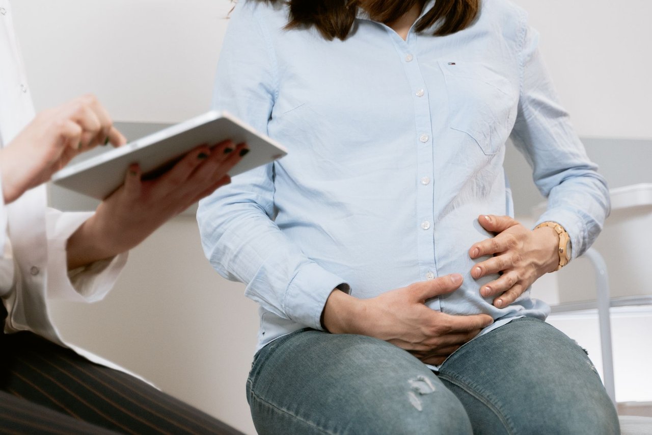 Gestante conversa com profissional de saúde durante uma consulta de pré-natal.