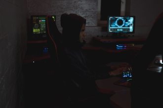 Profissional analisa dados em múltiplos monitores em uma sala escura de operações de cibersegurança.