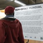 Pessoa observa informações sobre conscientização em saúde mental durante uma exposição fotográfica.
