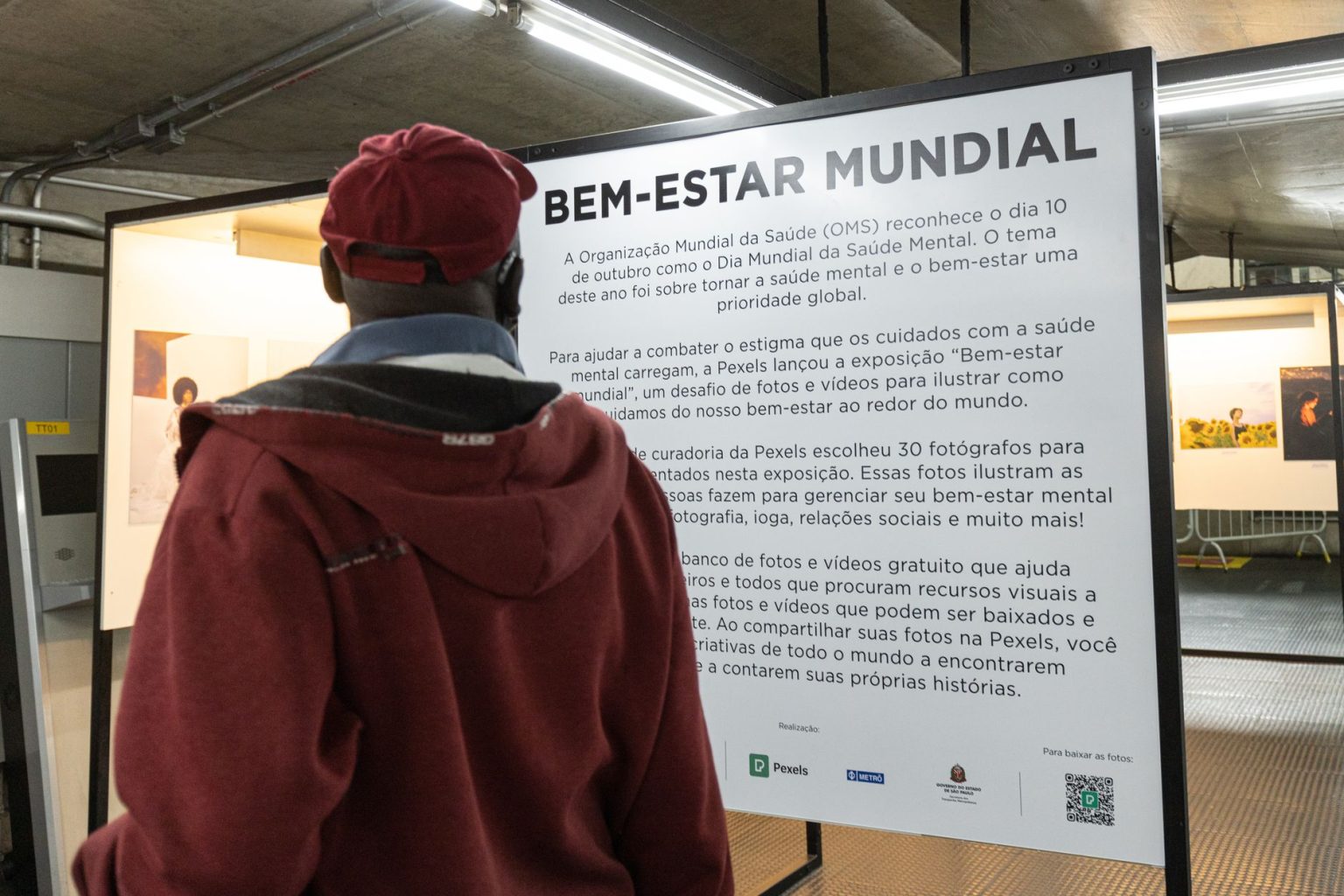 Pessoa observa informações sobre conscientização em saúde mental durante uma exposição fotográfica.