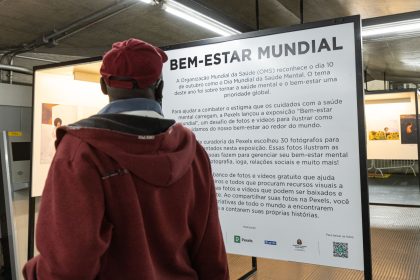 Pessoa observa informações sobre conscientização em saúde mental durante uma exposição fotográfica.