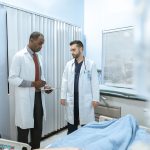 Dois profissionais de saúde analisam o prontuário de um paciente em uma sala hospitalar.