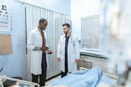 Dois profissionais de saúde analisam o prontuário de um paciente em uma sala hospitalar.