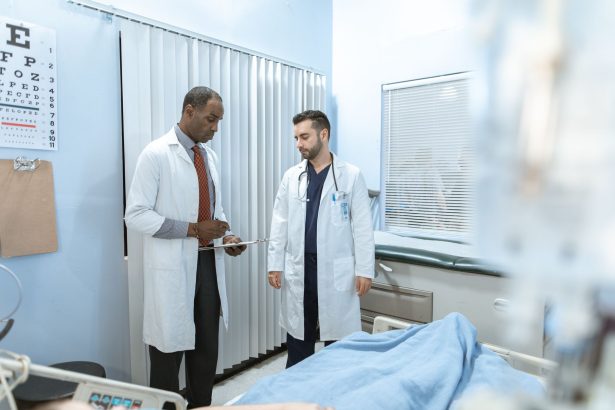 Dois profissionais de saúde analisam o prontuário de um paciente em uma sala hospitalar.