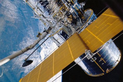 Espaçonave com painéis solares orbitando a Terra, vista contra o espaço.